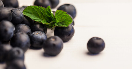 Close-up of fresh blueberries and leaves against white background, copy space