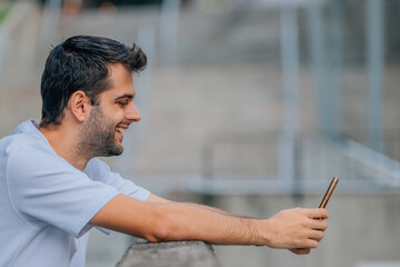 young man in profile on the street with mobile phone