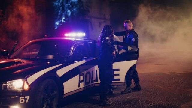 Two Police Officers Arrest Suspect, Put Him in Patrol Сar. Officers of Law Handcuff Dangerous Criminal on City Street. Officers of the Law and Under Arrest Felon, Fight Crime. Cinematic Slow Motion