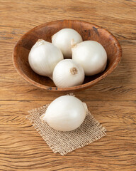 White onions in a bowl over wooden table