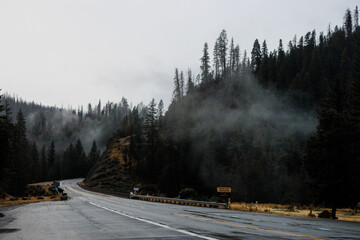 Thin clouds over the empty mountain road in California. Dramatic misty road in the evening