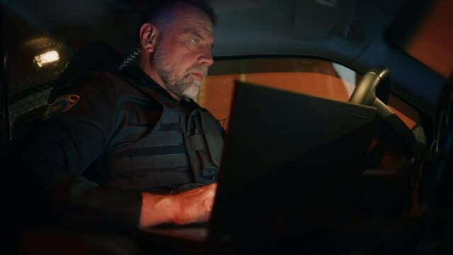 Inside Police Traffic Patrol Squad Car: White Male Police Officer on Duty Uses Laptop to Check Crime Suspect Background, License Numbers, License and Registration. Officer of the Law Fight Crime
