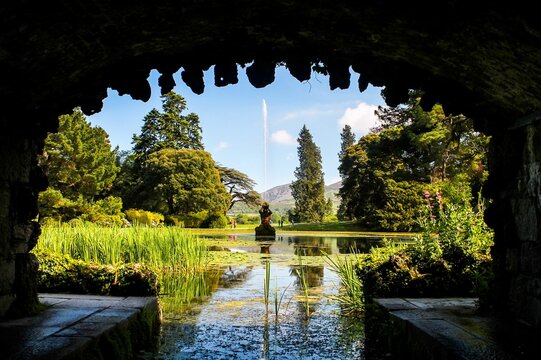 Amazing shot of the fountain in Powerscourt House and Gardens in Ireland seen through an arch