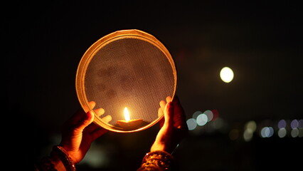 Woman hand holding Karwa Chauth strainer for the Karwa Chauth celebration on the night. Karwa...