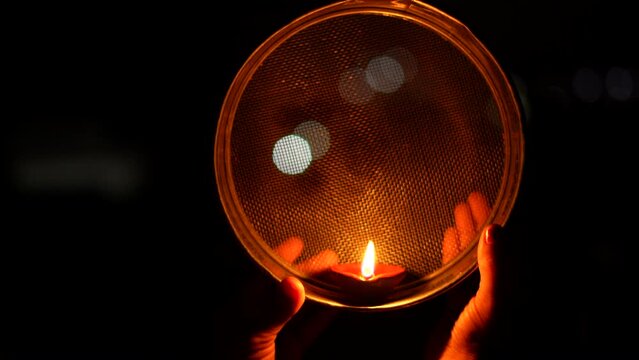 Woman hand holding Karwa Chauth strainer for the Karwa Chauth celebration on the night. Karwa Chauth strainer and Diya oil lamps for the Karwa Chauth celebration on the night
