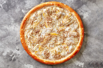 Sweet pizza with condensed milk, banana, peach, coconut shavings and almond flakes on gray surface
