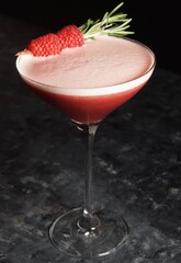 Martini glass cocktail garnished with raspberries
