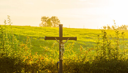 Crucifix in a green hilly meadow under a romantic sky at sunrise in autumn, Voeren, Limburg, Belgium, October, 2022