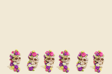Creative seamless pattern made of realistic human skulls with colorful flowers on pastel beige background. Aesthetic Mexican Day of the Dead (Dia De Los Muertos) or Halloween concept.