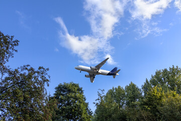 Airplane  in blue sky with light clouds over the house