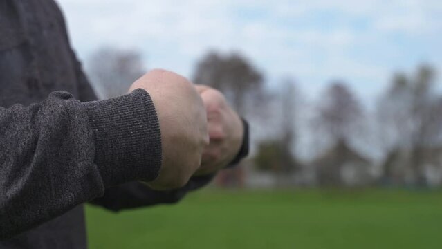 a man in a gray sports suit warms up before training at the stadium. an athlete prepares for a competition on an open sports field. a crossfitter warms up his hands before exercise.