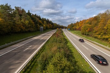 Autumn highway - cars are driving fast over a german Autobahn with colorful fall colors.