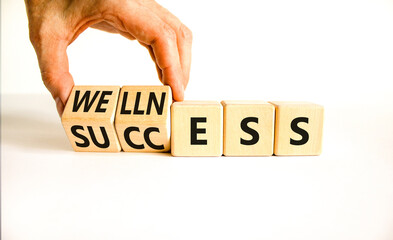 Wellness for success symbol. Concept words Wellness and Success on wooden cubes. Businessman hand. Beautiful white table white background. Business wellness for success concept. Copy space.