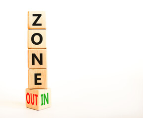 Zone in or out symbol. Concept words Zone in and Zone out on wooden cubes. Beautiful white table white background. Business zone in or out concept. Copy space.