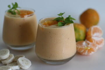Orange banana smoothie. Summer drink smoothie made of frozen bananas and fresh orange in almond milk, garnished with mint leaves