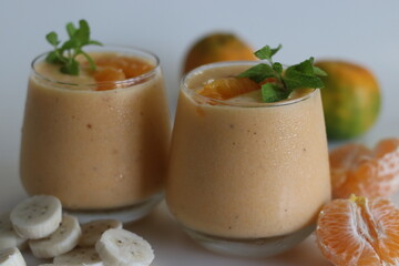 Orange banana smoothie. Summer drink smoothie made of frozen bananas and fresh orange in almond milk, garnished with mint leaves