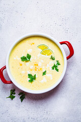 Corn soup in red pot. Vegan recipe concept.