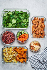 Vegan meal prep containers with  marinated tofu, beans, baked vegetables, green salad and vegetable sticks.