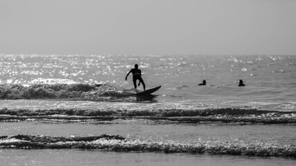 A man is surfing on a surfboard in Agadir beach in black and white