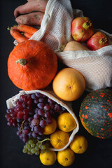 Various healthy autumnal food in reusable mesh bags. Top view, dark background.