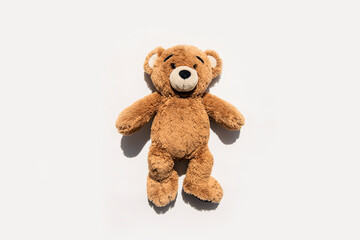 Soft toy bear lies on a white background. Top view, flat lay