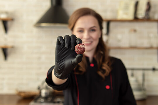 Woman holds candy. Soft focus. Professional pastry chef or chocolatier