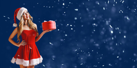 Woman wearing stylish red dress of Christmas costume posing with gift box in snow - Powered by Adobe