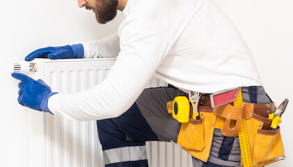 Portrait Of Mid-adult Male Plumber Repairing Radiator With Wrench.