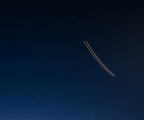 The trail from the plane at night in the starry sky at long exposure, cloudless winter night