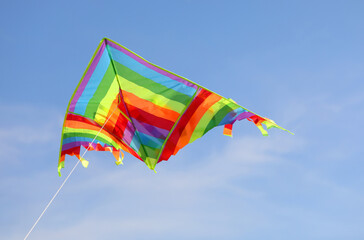 kite flies high in the blue sky tied to a string