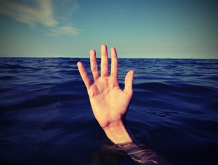 hand on the sea  of a person who is drowning and seeks help