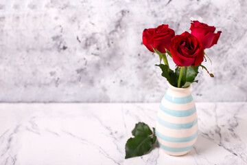 Background with red colorful summer roses  flowers against grey textured background in  vase. Selective focus. Still life. Place for text.