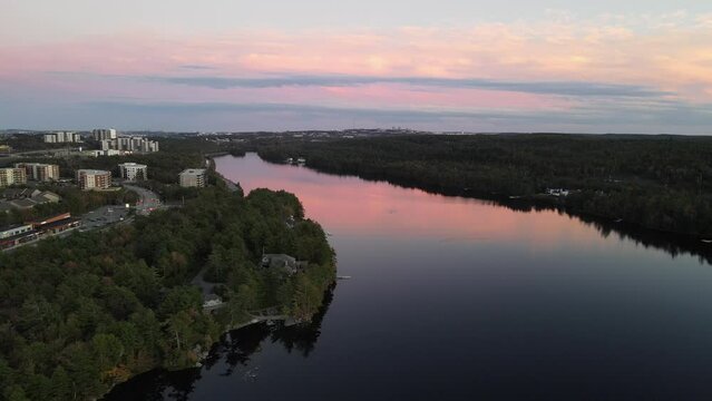 Aerial of a pink sunset over the river surrounded by trees and a town.