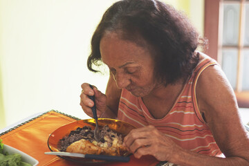 Poor elderly Brazilian woman having lunch
