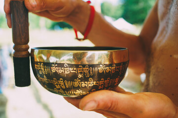 Tibetan singing bowl in the hands of a man, a musical instrument for meditation