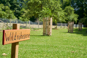 Wildlife resting zone in park in front of trees in the sunny summer. Area serves for the protection and recreation of animals.Translation on the Sign: Wildlife Rest Area