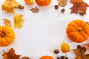 Pumpkins with fall leaves over white background. Top view.