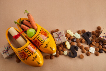 Saint Nicholas - Sinterklaas day with shoe, carrot and traditional sweets on caramel background