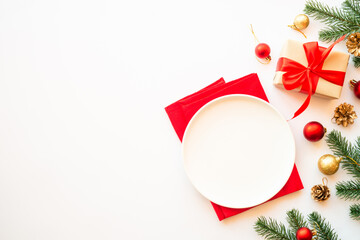 Christmas food, christmas table setting with white plate, present box and christmas decorations on white background. Top view.