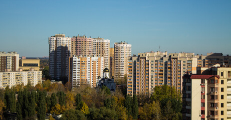 Fototapeta na wymiar Urban landscape - panoramic view of residential multi-storey modern houses among autumn trees on a sunny October day and copy space