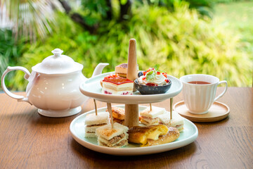 Afternoon tea with fresh cakes, pastries and sandwiches with hot tea