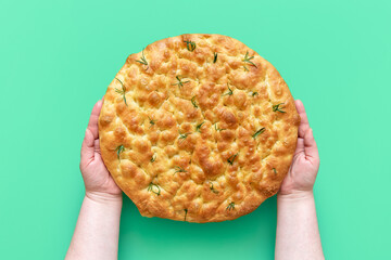 Focaccia with rosemary in woman hands, above view