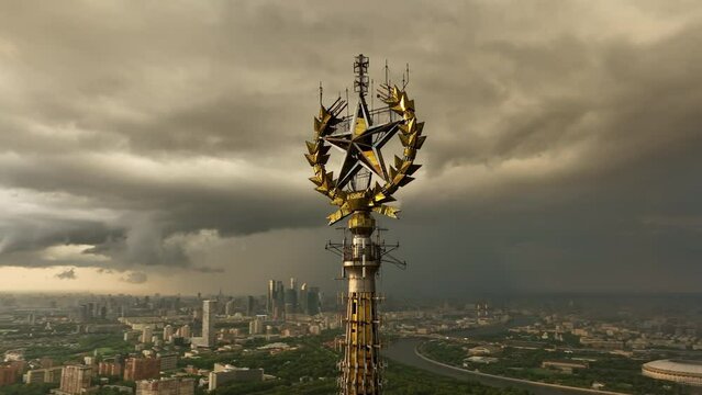 The five-pointed star is a Soviet symbol on top of the spire of the Moscow State University building. Stormy disturbing sky over the city. Epic aerial view.