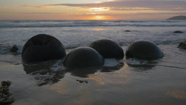 Sunrise on the Moeraki Boulders on the beach, in New Zealand