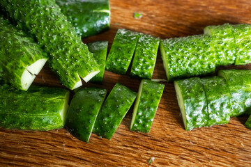 Preparation of beaten cucumbers. Cut halves of fresh cucumbers on a cutting wooden board.