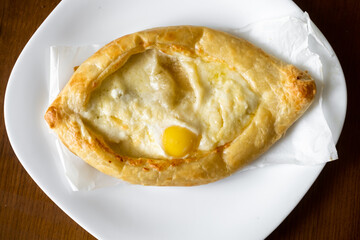 Adjarian khachapuri on a white plate. Traditional Georgian dish with cheese and chicken egg.