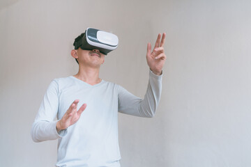 Young man using virtual reality headset. Isolated on grey background studio portrait. VR, future, technology, education online, studying . Man trying to touch objects in virtual reality , 