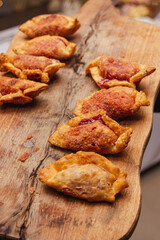 Empanadas fritas en grasa sobre tabla de madera. Comida típica argentina