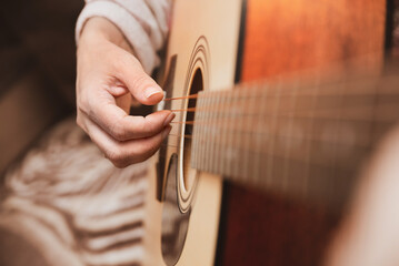 Woman's fingers touch guitar strings, woman learns to play guitar by herself through online...
