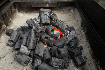 Shallow depth of field (selective focus) details with barbecue charcoal being lit up and prepared for cooking.
